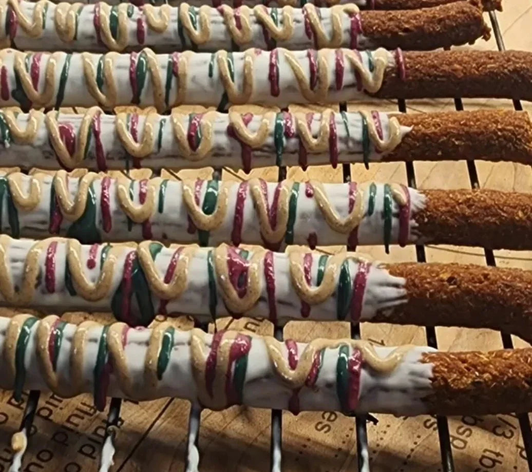 Gluten-free dog treats with festive red, green, and white icing on cooling rack